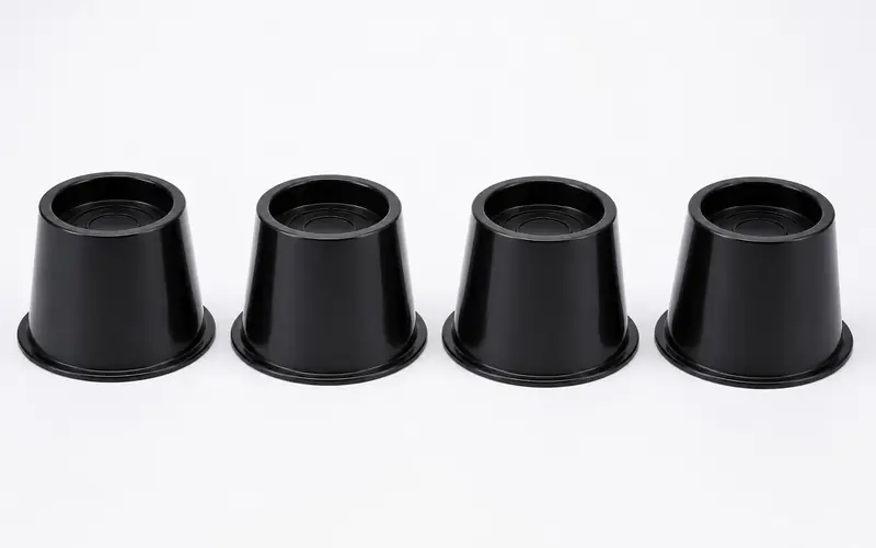 Illustration of four black plastic bed risers in a row.