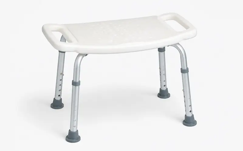 Illustration of a white shower stool with side handles and adjustable aluminium legs. Shows the type of product, not the exact brand or model.