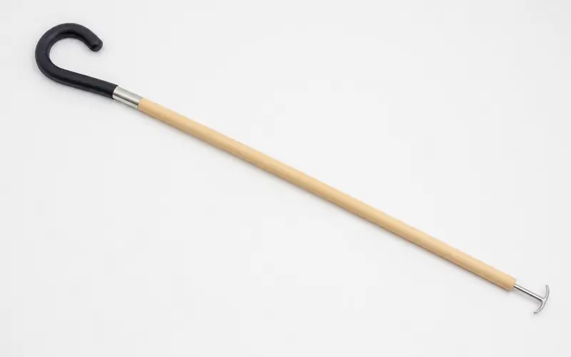 Illustration of a wooden dressing stick with a hook at each end.