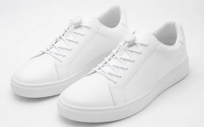 Illustration of white trainers laced with elastic no-tie laces and lock toggles.
