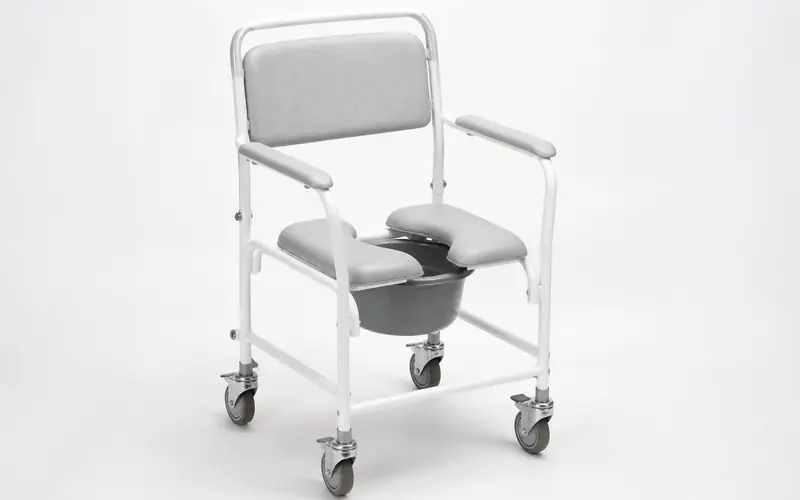 Illustration of a white wheeled shower commode chair with armrests and a padded seat. Shows the type of product, not the exact brand or model.