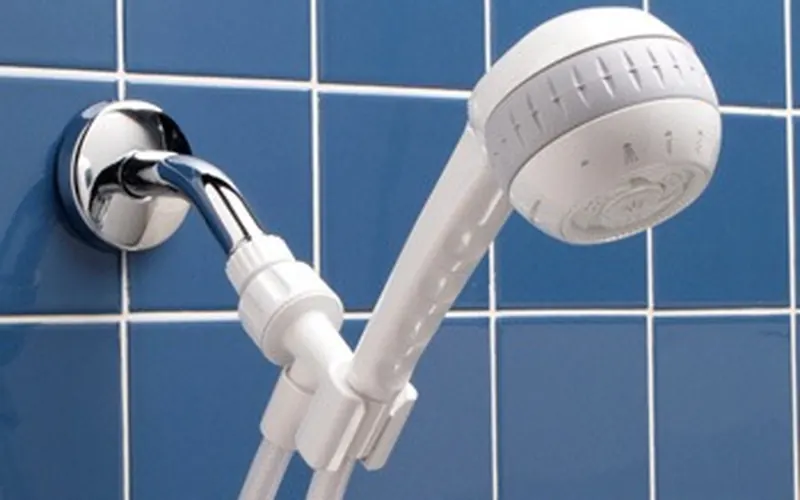 Photo of a white handheld shower head on a hose, held in a wall bracket.